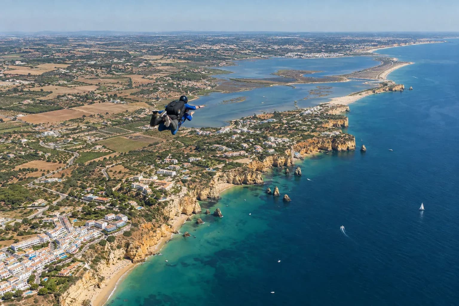 Two tandem skydivers in free fall high above the Algarve coastline