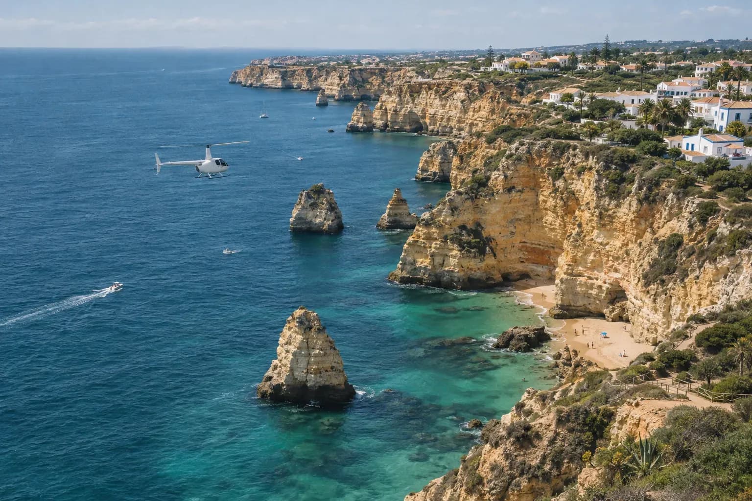 A small white helicopter flying low over golden cliffs and coves